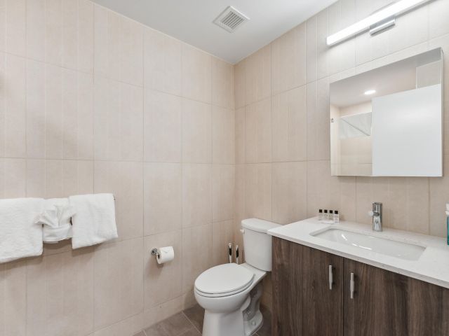A clean bathroom with a toilet, sink, mirror, and towels.