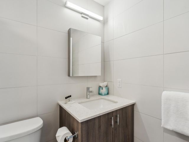 A modern bathroom with a toilet, sink, and cabinet.