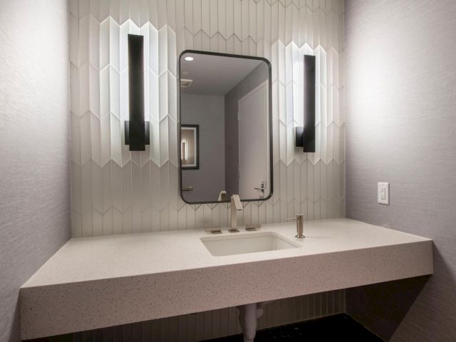 A bathroom sink area with a large mirror and lights on either side