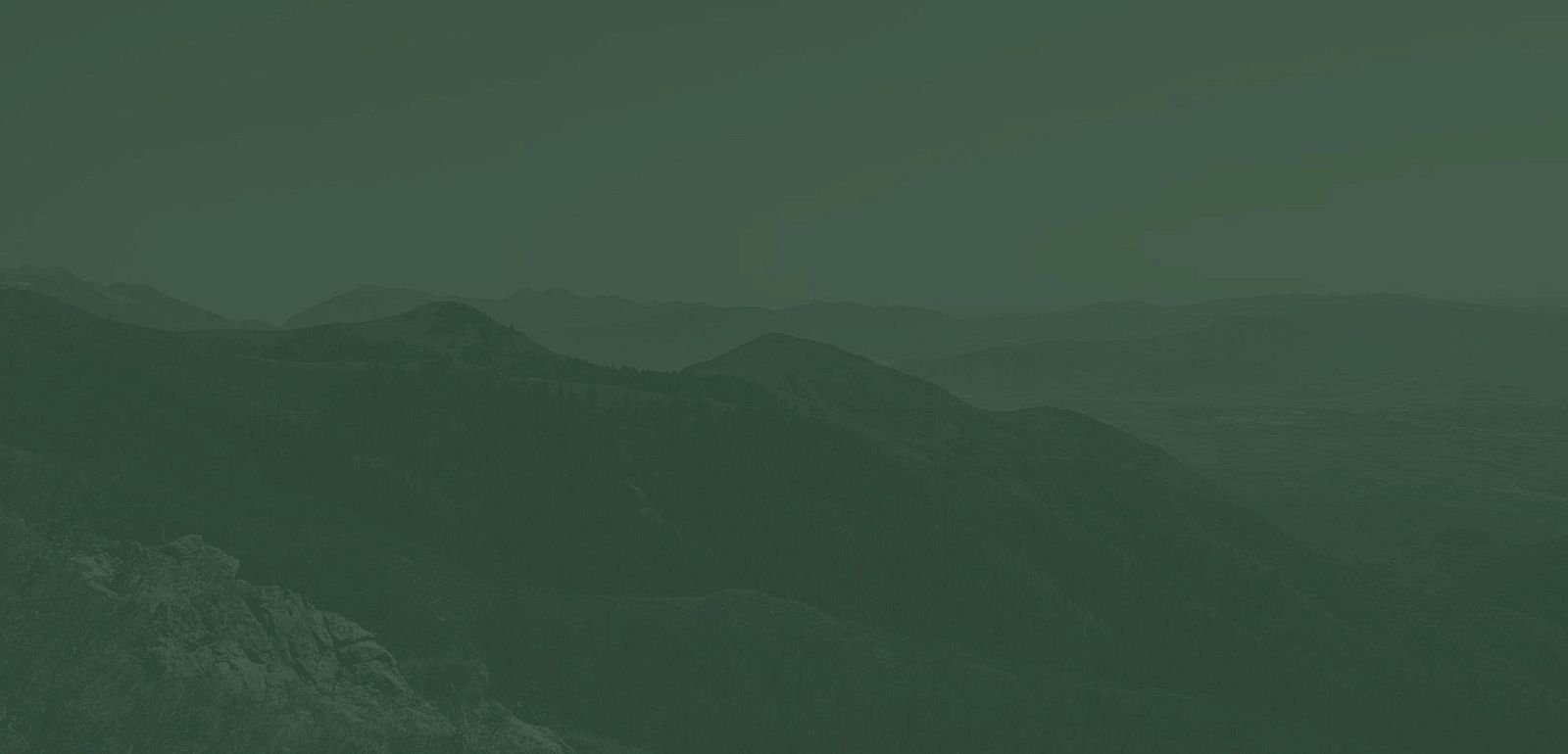 The image depicts a mountainous landscape with multiple peaks and a valley below, all under a green-tinted filter.